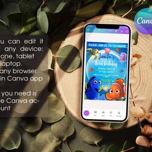 May include: A mobile phone screen displaying a blue and orange Finding Nemo themed birthday invitation for a third birthday party. The invitation includes the text "Please join us to celebrate Jennifer's third birthday" and the date and time of the party. The invitation is on a white background with a blue and orange border. The phone is on a wooden surface with green leaves.