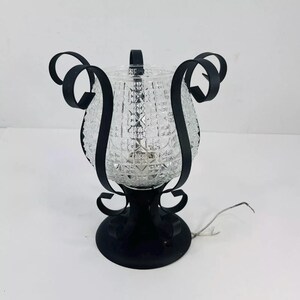 May include: A black metal lamp with a clear glass shade. The shade has a diamond pattern and the base has a decorative scroll design.