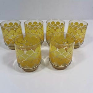 May include: Set of six yellow glass tumblers with a white geometric pattern. The glasses have a rounded bottom and a straight side.