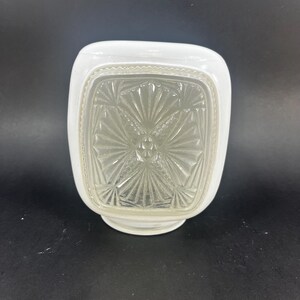 May include: A vintage white and clear glass light fixture. The fixture has a square shape with rounded edges and a decorative, textured glass panel. The white portion has a scalloped edge. The fixture is designed to be mounted on a ceiling or wall.