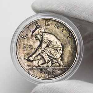 May include: A silver coin with a depiction of a man panning for gold. The coin reads "LIBERTY" at the top, "IN GOD WE TRUST" in the center, and "CALIFORNIA'S DIAMONDS JUBILEE 1925" at the bottom.