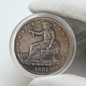 Könnte beinhalten: Eine Silberdollar-Münze mit dem Porträt einer Frau, die einen Zweig mit Blättern hält. Die Münze trägt die Inschrift "In God We Trust" und das Datum "1881".