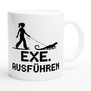 Könnte beinhalten: Weiße Keramiktasse mit einer schwarzen Silhouette einer Person, die einen Eidechsen spazieren führt. Der Text "EXE. AUSFÜHREN" ist auf die Tasse gedruckt.