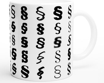 Könnte beinhalten: Weiße Keramiktasse mit einem schwarz-weißen Muster aus Paragraphenzeichen. Die Tasse hat einen Henkel auf der rechten Seite.