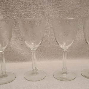 May include: Four clear glass wine glasses with a stemmed base and a round bowl.