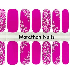 May include: A set of 10 pink nail wraps with a white floral design. The nail wraps are arranged in two rows of five. The text "Marathon Nails" is printed on the white strip between the two rows of nail wraps.