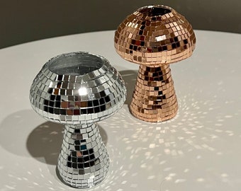 May include: Two decorative mushroom-shaped vases with a mirrored mosaic design. One vase is silver and the other is gold.