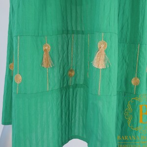 May include: A green skirt with gold embroidery and tassels. The skirt has a tiered design and is made of a lightweight fabric.