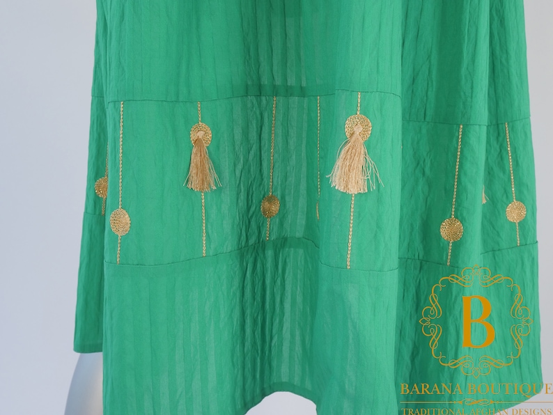 May include: A green skirt with gold embroidery and tassels. The skirt has a tiered design and is made of a lightweight fabric.