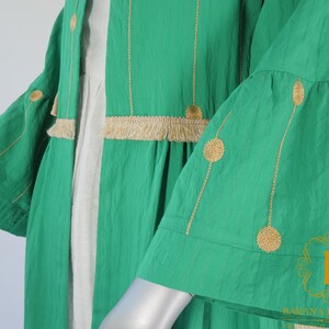 May include: A green long-sleeved cardigan with gold embroidery and fringe trim. The cardigan has a loose fit and a flowy silhouette.