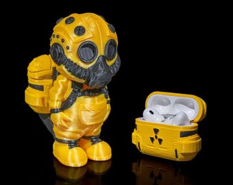 May include: A yellow and black 3D printed protective case for AirPods, featuring a cartoon character wearing a gas mask and a backpack. The case is shaped like a small, boxy container with a hinged lid.