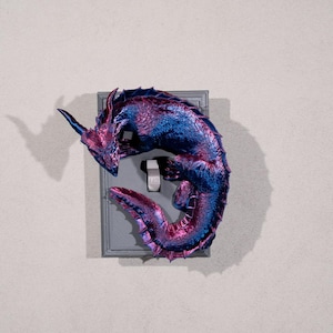 May include: A purple and blue dragon figurine is curled up around a light switch. The dragon is made of a shiny, iridescent material.