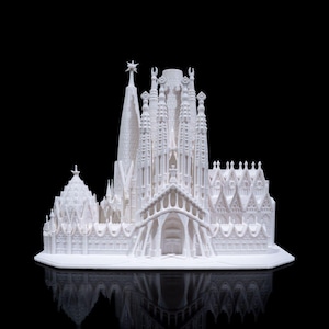 Op de afbeelding: Een wit 3D-geprint model van de Sagrada Família kerk in Barcelona, Spanje. Het model is gedetailleerd en bevat de iconische torens en torenspitsen van de kerk.