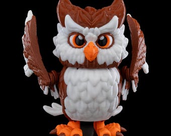 May include: A detailed owl figurine with outstretched wings. The owl is brown and white, with orange beak and feet. The owl has large, round eyes in orange. The figurine is set against a black background. A decorative item.