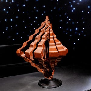May include: A brown wooden kinetic sculpture with a geometric design. The sculpture is on a black base and is spinning.