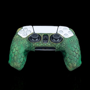 May include: A white PlayStation 5 DualSense controller with a green and brown textured skin that resembles a dragon scale pattern.