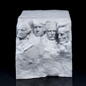 Könnte beinhalten: Ein weißes, modelliertes Modell des Mount Rushmore, das die Gesichter von vier Präsidenten zeigt, die in den Fels gehauen sind. Die Präsidenten sind George Washington, Thomas Jefferson, Theodore Roosevelt und Abraham Lincoln.