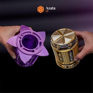 May include: Two 3D printed containers, one purple with a star-shaped top and the other gold with a segmented top. The containers are both intricate and detailed, showcasing the capabilities of 3D printing. The text "Azata 3D" is visible in the top right corner of the image.
