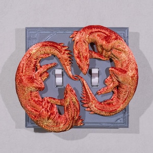 Puede incluir: Una tapa de interruptor de luz con un diseño impreso en 3D de cuatro dragones rojos y dorados entrelazados alrededor del interruptor.