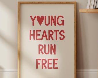 May include: A framed print with the text "YOUNG HEARTS RUN FREE" in red lettering with a red heart replacing the "O" in "YOUNG". The print is on a white background and is framed in a light wood frame.