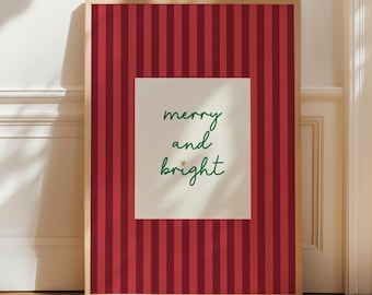 May include: A rectangular framed wall art piece featuring a vertical red and dark red striped background. In the center, a cream-colored rectangular inset displays the green cursive text merry and bright with a small gold star above the word bright.