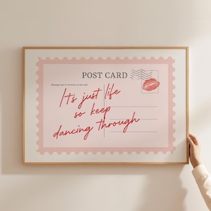 May include: A framed postcard print with a pink and white design. The text reads "It's just life so keep dancing through" in a handwritten style. A red lip print and postage stamp are also featured.