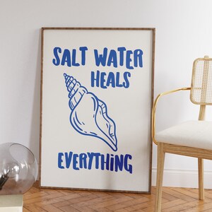 May include: A framed print with a white background and blue text that reads "Salt Water Heals Everything". A blue seashell illustration is centered on the print.