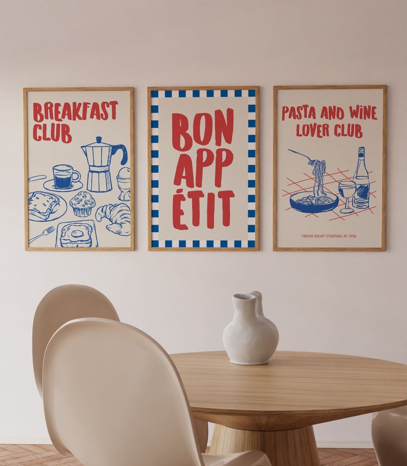 Op de afbeelding: Drie ingelijste kunstprints met een voedselthema. De linkerprint zegt "BREAKFAST CLUB" met illustraties van ontbijt in blauw. De middelste print zegt "BON APP&Eacute;TIT" in rood. De rechterprint zegt "PASTA AND WINE LOVER CLUB" met illustraties in blauw.