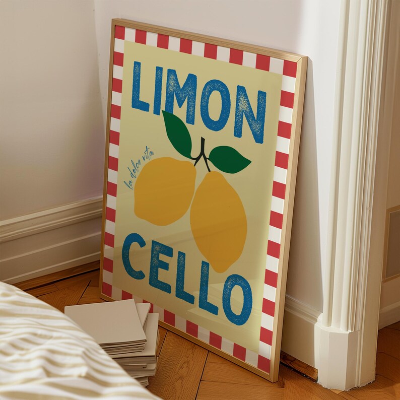 May include: A framed print with a red and white striped border. The print features a yellow lemon with the text "Limon Cello" in blue and the text "la dolce vita" in smaller blue text.