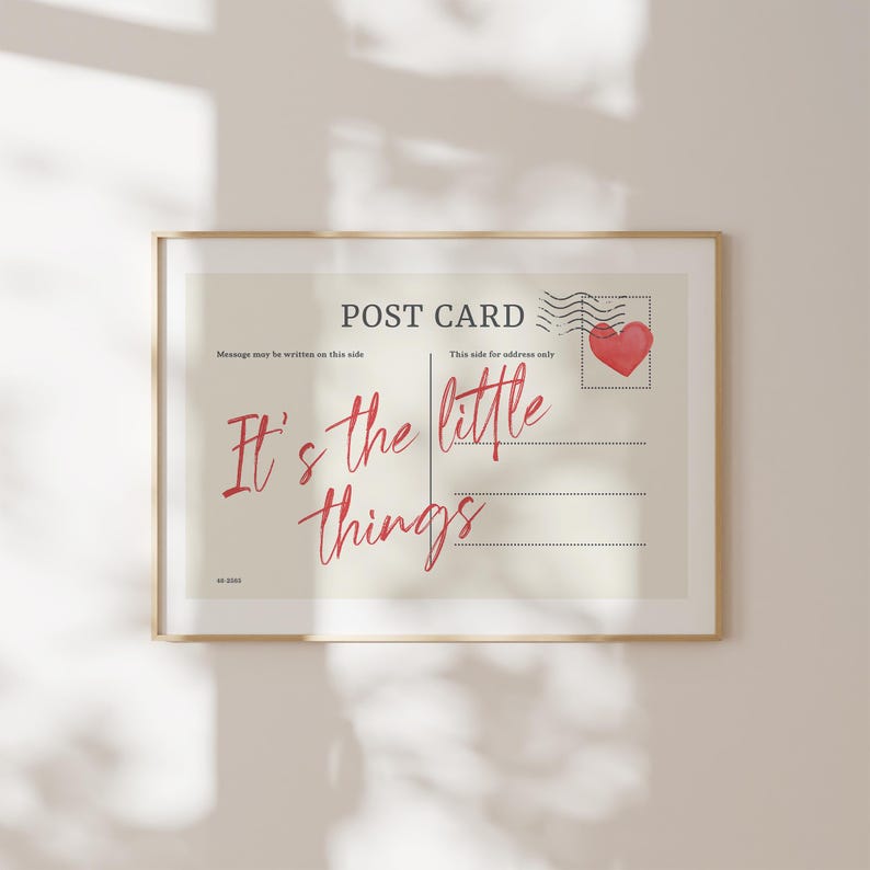 Pu&ograve; includere: Stampa incorniciata con design di cartolina. Il testo "POST CARD" &egrave; in alto, con "It's the little things" in corsivo rosso. Sono visibili anche un timbro a forma di cuore rosso e linee per la scrittura.