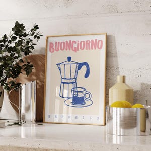 Pode incluir: Uma impress&atilde;o emoldurada com uma ilustra&ccedil;&atilde;o azul e branca de uma cafeteira e uma x&iacute;cara de caf&eacute;. O texto "BUONGIORNO ESPRESSO" est&aacute; impresso em rosa e azul.