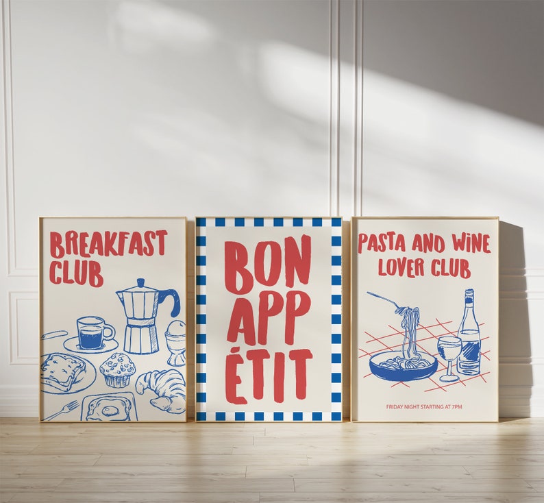 Op de afbeelding: Drie ingelijste kunstprints met rode en blauwe illustraties op een cr&egrave;mekleurige achtergrond. De prints luiden "BREAKFAST CLUB", "BON APP&Eacute;TIT" en "PASTA AND WINE LOVER CLUB". De pastaprint bevat de tekst "FRIDAY NIGHT STARTING AT 7PM".