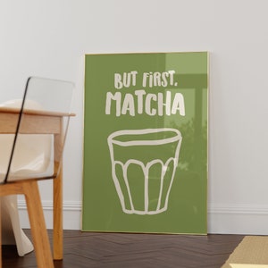 May include: A framed green poster with white text that reads "But first, matcha" and a white illustration of a cup of matcha.