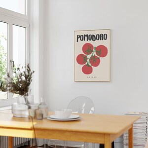 May include: A framed poster with a minimalist design featuring a red tomato vine with the text "POMODORO NAPLES" in black.