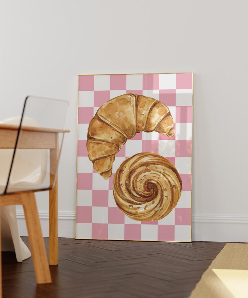 K&ouml;nnte beinhalten: Eine Aquarell-Illustration eines Croissants und eines Strudelgeb&auml;cks auf einem rosa-wei&szlig; karierten Hintergrund.