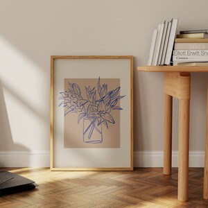 May include: A framed print of a blue line drawing of flowers in a vase on a light brown background.
