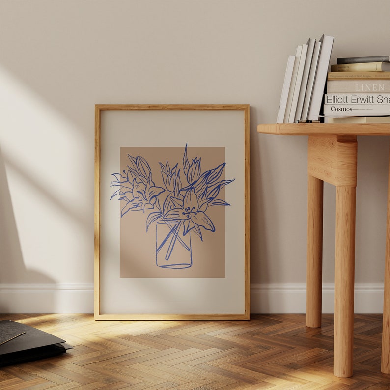 May include: A framed print of a blue line drawing of flowers in a vase on a light brown background.