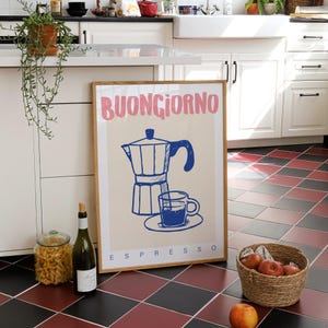 Pode incluir: Uma impress&atilde;o emoldurada com o texto "BUONGIORNO ESPRESSO" em letras rosa e azul. A impress&atilde;o apresenta uma ilustra&ccedil;&atilde;o azul e branca de uma cafeteira e uma x&iacute;cara de caf&eacute;.
