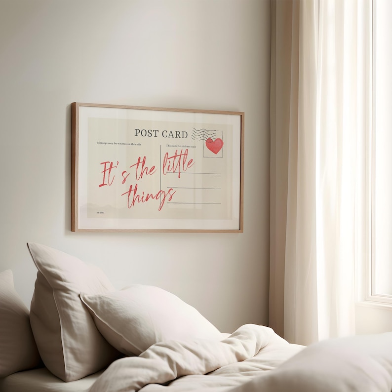 Pu&ograve; includere: Stampa incorniciata di una cartolina con la scritta "It's the little things" in rosso. Il design della cartolina include un timbro a forma di cuore rosso e linee per la scrittura. La cornice &egrave; in legno chiaro, appesa a una parete bianca.