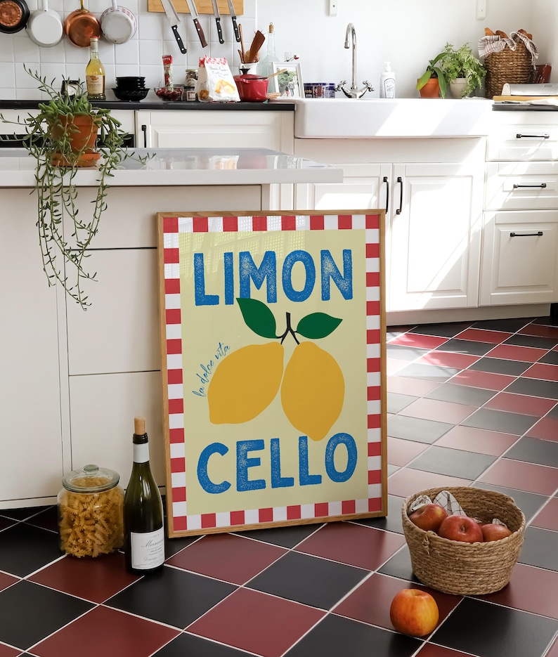 May include: A framed print with a red and white checkered border. The print features a yellow background with the text "LIMON la dolce vita CELLO" in blue and white. Two yellow lemons with green leaves are depicted on the print.