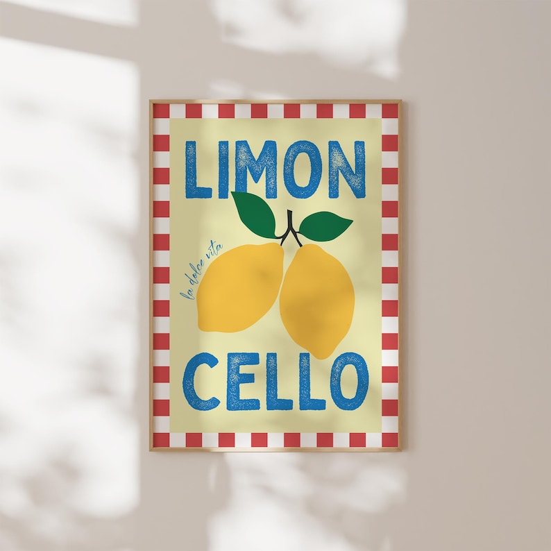 May include: A yellow and white poster with red and white checkered border. The poster says "Limon Cello" in blue text with the words "la dolce vita" in smaller text. Two yellow lemons with green leaves are pictured in the center.
