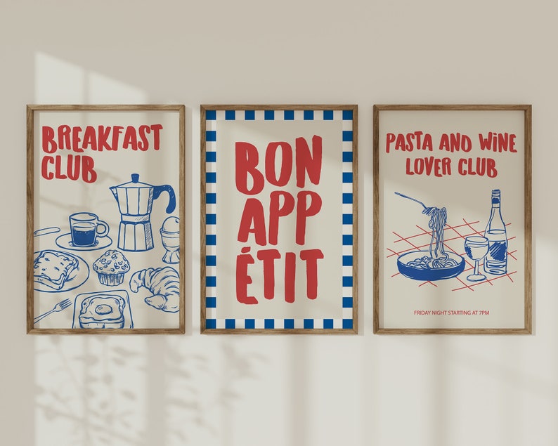 Op de afbeelding: Drie ingelijste kunstprints met een retro-ontwerp. De prints tonen rode en blauwe illustraties en tekst op een cr&egrave;mekleurige achtergrond. E&eacute;n zegt "Breakfast Club", een andere "Bon App&eacute;tit" en de derde "Pasta and Wine Lover Club". De frames zijn lichtbruin.