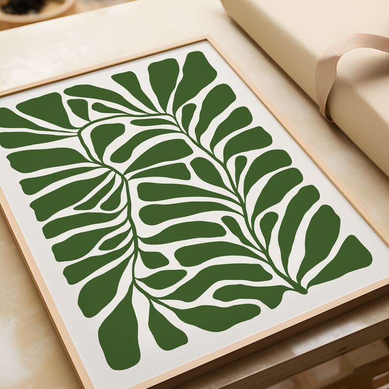 May include: A framed print featuring a stylised green leaf design on a white background.