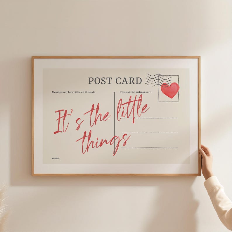 Pu&ograve; includere: Una stampa incorniciata che assomiglia a una cartolina vintage. Il design presenta le parole "It's the little things" in corsivo rosso, un timbro a forma di cuore rosso e il testo "POST CARD". La cornice &egrave; di colore marrone chiaro.
