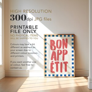 Op de afbeelding: Een ingelijste print met de woorden "BON APP&Eacute;TIT" in rode, vette letters op een cr&egrave;mekleurige achtergrond. De lijst is lichtbruin en de print heeft een blauw-witte geblokte rand. De tekst "HIGH RESOLUTION 300 dpi JPG files" is ook zichtbaar.