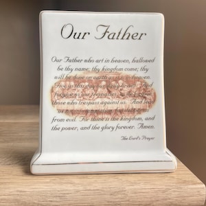 May include: A white ceramic mug with a black handle and the text "But First, Coffee" in a bold, black font. The mug is set against a blurred background, suggesting a cozy setting.