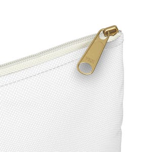 Puede incluir: Bolsa blanca con cremallera y un tirador de cremallera dorado. El tirador de la cremallera tiene el texto "YKK" en &eacute;l.