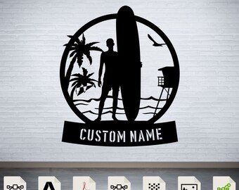 Könnte beinhalten: Schwarz-weiße Silhouette eines Surfers, der mit einem Surfbrett vor Palmen und einem Rettungsturm steht. Das Design ist in einem Kreis mit dem Text "CUSTOM NAME" darunter. Das Bild ist auf einem weißen Ziegelmauerhintergrund.