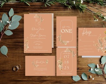 Puede incluir: Un conjunto de papelería de boda de color terracota, que incluye invitaciones, tarjetas de confirmación de asistencia y notas de agradecimiento, adornadas con diseños florales y detalles dorados. La invitación dice "Olivia Jones & Stephen Davies". También hay dos anillos de boda de oro.
