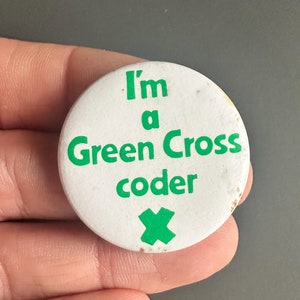 May include: White button with green text that reads "I'm a Green Cross coder" with a green X at the bottom.